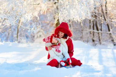 Anne ve bebek atlı kızak yolculuğu. Çocuk ve kızakla anne. Yürümeye başlayan çocuk sürme balyoz. Çocuklar açık havada karda oynamak. Karlı parkta çocuklar kızak. Açık kış eğlence aile Noel tatili için. 