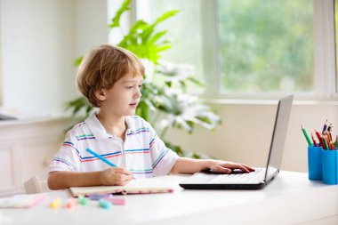 Çevrimiçi uzaktan öğrenme. Bilgisayarlı okul çocukları öğretmen ve sınıf grubuyla görüntülü konuşma yapıyorlar. Çocuk evden ders çalışıyor. Evde eğitim. Eğitim için modern aletler. Ekran zaman denetimi.