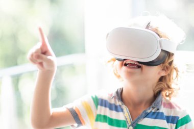 Sanal gerçeklik gözlüklü çocuk. Çocuklar için video kayıt seti. Küçük çocuk bilgisayar oyunu oynuyor. Modern dijital cihazla öğreniyorum. Çocuklar elektronik aletlerle ders çalışırlar. Gelecek eğitim konsepti. Eğlenceli oyun..