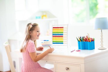 Çocuk evde ödev yapıyor. Ahşap renkli abaküsü olan küçük bir çocuk matematik egzersizi yapıyor toplama ve sayma yapıyor. Çocuklar çalışır ve öğrenir. Anaokulu çocuğu yazıp okuyor. Okula geri dön..