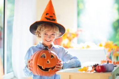 Cadılar Bayramı için aile dekorasyonu evi. Çocuklar için cadılar bayramı sanatı ve el sanatları. Şeker mi şaka mı dekorasyonu mu? Çocuklar evi dekore eder. Cadı kostümlü ve şapkalı çocuklar. Ürkütücü Cadılar Bayramı eğlencesi.