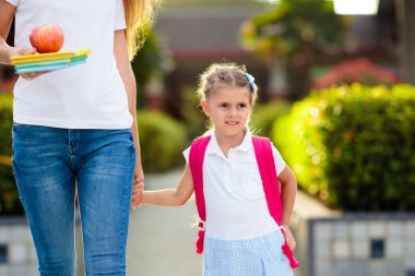 Anne ve çocuklar okuldan sonra. Anaokulundan ya da anaokulundan sonra çocukları alan genç bir anne. Öğrencileri toplayın. Oğlan ve kız okul bahçesinde ailelerine koşuyorlar..