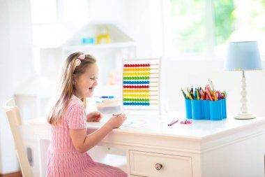 Çocuk evde ödev yapıyor. Ahşap renkli abaküsü olan küçük bir çocuk matematik egzersizi yapıyor toplama ve sayma yapıyor. Çocuklar çalışır ve öğrenir. Anaokulu çocuğu yazıp okuyor. Okula geri dön..