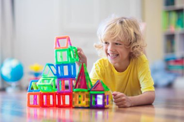 Çocuk manyetik yapı taşlarıyla oynuyor. Küçük çocuk kule inşa ediyor. Çocuklar için eğitici oyuncaklar. Küçük çocuklar için inşaat oyuncakları. Geometri ve matematik oyunu. Okul öncesi eğlencesi.