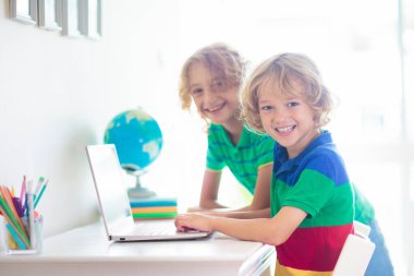 Bilgisayarda ödev yapan bir çocuk. Çevrimiçi sınıf. Evde eğitim ve uzaktan eğitim. Küçük okul çocuğu monitörde okuyor. Çocuklar video oyunu oynar. Oyun ve ekran zaman denetimi.