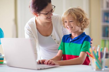 Bilgisayarda ödev yapan bir çocuk. Çevrimiçi sınıf. Evde eğitim ve uzaktan eğitim. Küçük okul çocuğu monitörde okuyor. Çocuklar video oyunu oynar. Oyun ve ekran zaman denetimi.