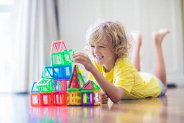 Çocuk manyetik yapı taşlarıyla oynuyor. Küçük çocuk kule inşa ediyor. Çocuklar için eğitici oyuncaklar. Küçük çocuklar için inşaat oyuncakları. Geometri ve matematik oyunu. Okul öncesi eğlencesi.