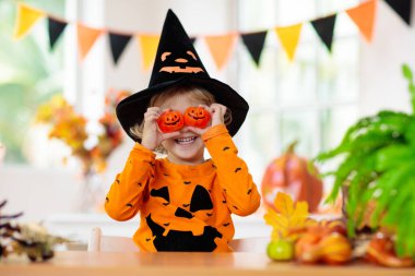 Cadılar Bayramı kostümlü çocuk. Çocuklar şeker mi şaka mı? Balkabağı fenerli küçük çocuk. Cadı şapkalı bebek. Sonbahar tatili dekorasyonu. Dökülen yapraklar ve kabaklarla ev şenliği. 