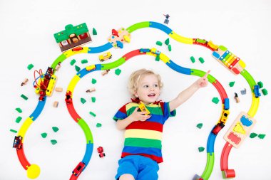 Çocuklar oyuncak tren yolu ile oynarlar. Çocuk renkli gökkuşağı ahşap trenleriyle oynuyor. Küçük çocuk için oyuncaklar. Anaokulunda ya da anaokulunda demiryolu inşaatı yapan anaokulunda. Anaokulu eğitim oyunları.