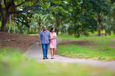 Aşık genç Hintli çift. Güneşli yaz parkında yürüyen erkek ve kadın. Tropik bir tatil köyünde balayı. Karı koca dışarı çıkar..