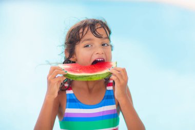 Yüzme havuzunda karpuzlu bir çocuk. Yaz güneşi ve su eğlencesi. Çocuklar için sağlıklı meyve atıştırmalığı. Aile tatilinde tropik meyveler. Çocuklarla seyahat et. Plaj tatilindeki küçük kız..