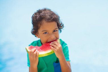 Yüzme havuzunda karpuzlu bir çocuk. Yaz güneşi ve su eğlencesi. Çocuklar için sağlıklı meyve atıştırmalığı. Aile tatilinde tropik meyveler. Çocuklarla seyahat et. Plaj tatilindeki küçük kız..