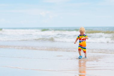 Tropik sahilde oynayan çocuk. Küçük çocuk kazma kum deniz desteklemek. Aile yaz tatili. Çocuklar su ile oynamak ve oyuncakları kum. Okyanus ve Adası eğlenceli. Küçük çocuklarla seyahat. Asya tatil.