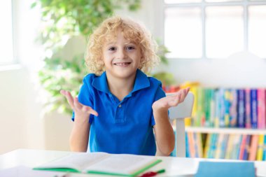 Okul çocuğu ödevini yapıyor. Evden çevrimiçi uzaktan öğrenme. Bilgisayarlı çocuklar öğretmen ve sınıf grubuyla görüntülü konuşma yapıyorlar. Çocuk eğitimi. Evde eğitim. Çocuk okuması.