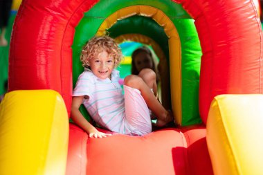 Çocuk renkli trambolinde atlıyor. Çocuklar anaokulundaki doğum günü partisinde şişme şatoya atlayıp küçük çocuklar için oyun merkezine giriyorlar. Küçük çocuk yazın dışarıda oynuyor..