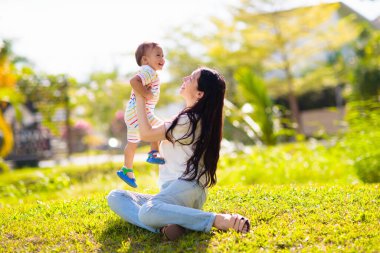 Sunny Park 'ta anne ve oğlu. Dışarıda oynayan Asyalı bir aile. Anne kucağında küçük bir çocuk var. Genç bir kadın ve sevimli bir çocuk oynuyorlar ve gülüyorlar. Mutluluk ve sevgi. Anneler günün kutlu olsun..