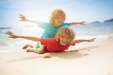 Tropik sahilde oynayan çocuk. Küçük kız kazma kum deniz desteklemek. Aile yaz tatili. Çocuklar su ile oynamak ve oyuncakları kum. Okyanus ve Adası eğlenceli. Küçük çocuklarla seyahat. Asya tatil.