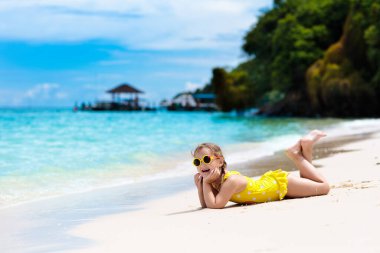 Tropik plajda oynayan bir çocuk. Deniz kıyısındaki küçük kız. Aile yaz tatili. Çocuklar su ve kum oyuncaklarıyla oynuyor. Okyanus ve ada eğlencesi. Küçük çocuklarla seyahat et. Asya tatili.