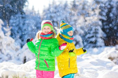 Çocuklar ile oynarken Kışın kar. Küçük kız ve erkek renkli ceket ve örme şapka Noel'de kar taneleri kış Park yakalamak. Çocuklar karlı ormanda atlamak. Kar topu mücadele çocuklar için.