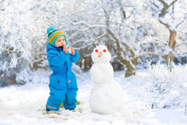 Çocuklar kardan. Kar bina çocuklar oynarken açık havada güneşli karlı kış gün dostum. Noel tatil açık aile eğlencesi. Erkek ve kız kar topları oyun. Kış giyim bebek ve yürümeye başlayan çocuk için.