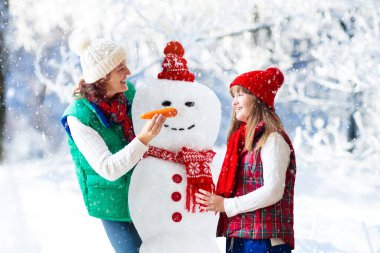 Aile Kardan Adam 'ı. Anne ve çocuk kardan adam yapar. Anne ve çocuk karlı kış gününde dışarıda oynuyorlar. Dağlarda Noel tatili için açık hava eğlencesi. Çocuklar karlı kış parkında oynuyorlar.