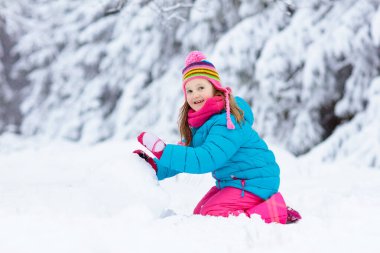 Karlı kış parkında kardan adam yapan bir çocuk. Çocuklar karda oynar. Kar yağdıktan sonra kış bahçesinde kardan adam yapan renkli ceketli ve şapkalı küçük kız. Soğuk kış gününde açık hava eğlencesi.