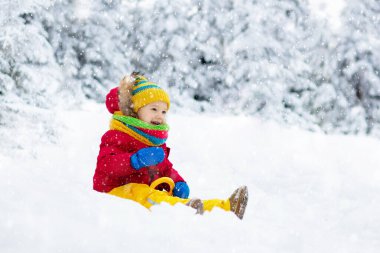 Küçük çocuk kızakla gezintiye çıkıyor. Çocuk kayağı. Kızak süren küçük bir çocuk. Çocuklar karda dışarıda oynarlar. Çocuklar kışın Alp dağlarında kızak kullanırdı. Aile Noel tatili için açık hava eğlencesi.