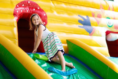 Çocuk renkli trambolinde atlıyor. Çocuklar anaokulundaki doğum günü partisinde şişme şatoya atlayıp küçük çocuklar için oyun merkezine giriyorlar. Küçük çocuk yazın dışarıda oynuyor..