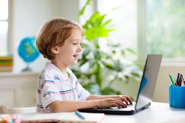 Çevrimiçi uzaktan öğrenme. Bilgisayarlı okul çocukları öğretmen ve sınıf grubuyla görüntülü konuşma yapıyorlar. Çocuk evden ders çalışıyor. Evde eğitim. Eğitim için modern aletler. Ekran zaman denetimi.