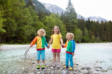 Nehri geçerken Alp dağlarında hiking çocuk. Çocuklar su Avusturya Mountain oynamak. Bahar aile tatili. Küçük erkek ve kız zammı izinde. Açık eğlenceli. Çocuklu Aktif istirahat.