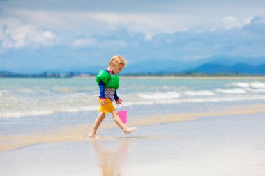 Tropik sahilde oynayan çocuk. Küçük çocuk kazma kum deniz desteklemek. Aile yaz tatili. Çocuklar su ile oynamak ve oyuncakları kum. Okyanus ve Adası eğlenceli. Küçük çocuklarla seyahat. Asya tatil.