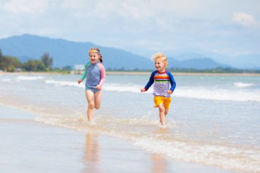 Tropik sahilde oynayan çocuk. Küçük kız kazma kum deniz desteklemek. Aile yaz tatili. Çocuklar su ile oynamak ve oyuncakları kum. Okyanus ve Adası eğlenceli. Küçük çocuklarla seyahat. Asya tatil.