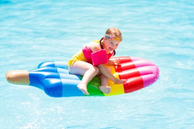 Şişme dondurma float tropikal tatil köyü Açık Yüzme havuzunda mutlu çocuk. Çocuklarla yaz tatili. AIDS yüzmek ve çocuklar için giyim. Su oyuncakları. Renkli salda yüzen küçük kız.