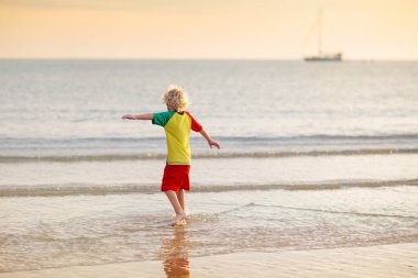 Okyanus sahilinde oynayan bir çocuk. Gün batımında dalgalara atlayan bir çocuk. Aile için deniz tatili. Yaz tatili boyunca egzotik adada koşan küçük çocuk.. 