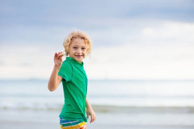 Tropik plajda oynayan bir çocuk. Deniz kıyısındaki küçük erkek bebek. Aile yaz tatili. Çocuklar su ve kum oyuncaklarıyla oynuyor. Okyanus ve ada eğlencesi. Asya 'da küçük çocuklarla seyahat et..