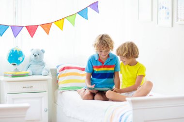 Tablet bilgisayarı olan çocuk. Çocuklar çevrimiçi çalışıyor. İki kardeş için yatak odası. Evde öğrenme ve öğrenme için elektronik cihaz. Bilgisayarlı küçük çocuk. Çocuklar için Gadget ekran zamanı. Evdeki çocuk.. 