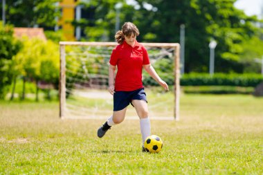 Çocuk futbol oynuyor. Çocuklar dışarıda futbol oynarlar. Yaz parkında top oynayan genç kız. Küçük çocuklar için sağlıklı bir aktivite. Okul spor kulübü takımı. Futbol Küçükler Ligi.