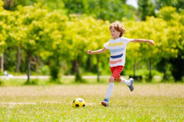 Çocuk futbol oynuyor. Çocuklar dışarıda futbol oynarlar. Küçük çocuk yaz parkında topa vuruyor. Küçük çocuklar için sağlıklı bir aktivite. Okul spor kulübü takımı. Futbol Küçükler Ligi.