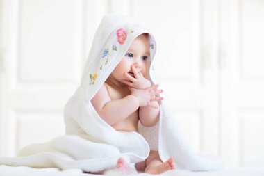 Beyaz güneşli yatak odasında sevimli bir bebek. Yeni doğmuş çocuk yatakta dinleniyor. Küçük çocuklar için çocuk odası. Çocuklar için tekstil ve yatak. Aile sabahı evde. Oyuncak ayıyla karnını doyururken doğan yeni çocuk..