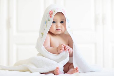 Beyaz güneşli yatak odasında sevimli bir bebek. Yeni doğmuş çocuk yatakta dinleniyor. Küçük çocuklar için çocuk odası. Çocuklar için tekstil ve yatak. Aile sabahı evde. Oyuncak ayıyla karnını doyururken doğan yeni çocuk..