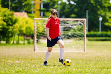 Çocuk futbol oynuyor. Çocuklar dışarıda futbol oynarlar. Yaz parkında top oynayan genç kız. Küçük çocuklar için sağlıklı bir aktivite. Okul spor kulübü takımı. Futbol Küçükler Ligi.