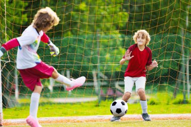 Çocuk futbol oynuyor. Çocuklar dışarıda futbol oynarlar. Küçük çocuk yaz parkında topa vuruyor. Küçük çocuklar için sağlıklı bir aktivite. Okul spor kulübü takımı. Futbol Küçükler Ligi.