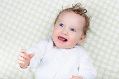 Beyaz güneşli yatak odasında sevimli bir bebek. Yeni doğmuş çocuk yatakta dinleniyor. Küçük çocuklar için çocuk odası. Çocuklar için tekstil ve yatak. Aile sabahı evde. Oyuncak ayıyla karnını doyururken doğan yeni çocuk..