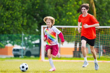 Çocuk futbol oynuyor. Çocuklar dışarıda futbol oynarlar. Küçük çocuk yaz parkında topa vuruyor. Küçük çocuklar için sağlıklı bir aktivite. Okul spor kulübü takımı. Futbol Küçükler Ligi.
