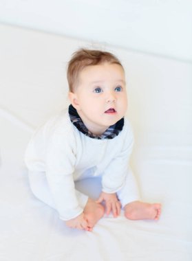 Beyaz güneşli yatak odasında sevimli bir bebek. Yeni doğmuş çocuk yatakta dinleniyor. Küçük çocuklar için çocuk odası. Çocuklar için tekstil ve yatak. Aile sabahı evde. Oyuncak ayıyla karnını doyururken doğan yeni çocuk..