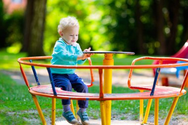 Çocuklar doğayı keşfeder. Çocuklar güneşli parkta oynarlar. Çocuk güzel bir yaz parkında oyun parkında. Aktif aile için açık hava eğlencesi. Çocuk sallanıyor ve kayıyor..