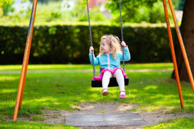 Çocuklar doğayı keşfeder. Çocuklar güneşli parkta oynarlar. Çocuk güzel bir yaz parkında oyun parkında. Aktif aile için açık hava eğlencesi. Çocuk sallanıyor ve kayıyor..