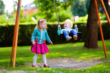 Çocuklar doğayı keşfeder. Çocuklar güneşli parkta oynarlar. Çocuk güzel bir yaz parkında oyun parkında. Aktif aile için açık hava eğlencesi. Çocuk sallanıyor ve kayıyor..