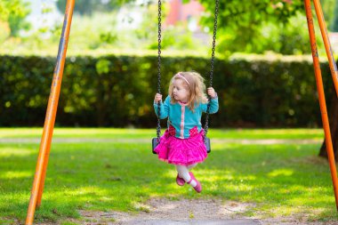 Çocuklar doğayı keşfeder. Çocuklar güneşli parkta oynarlar. Çocuk güzel bir yaz parkında oyun parkında. Aktif aile için açık hava eğlencesi. Çocuk sallanıyor ve kayıyor..