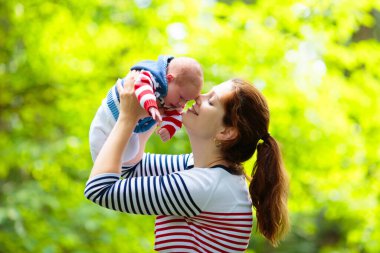 Bir park Holding yeni doğan bebek anne. Yeni doğan oğluyla bahçede oynayan anne. Aile çocuklarla oynamak açık havada. Genç kadın küçük çocuk sarılma. Ebeveynler ve çocuklar yaz aylarında eğleniyor.
